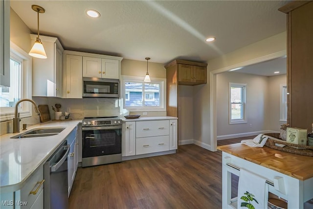 kitchen with a sink, recessed lighting, appliances with stainless steel finishes, hanging light fixtures, and dark wood-style flooring