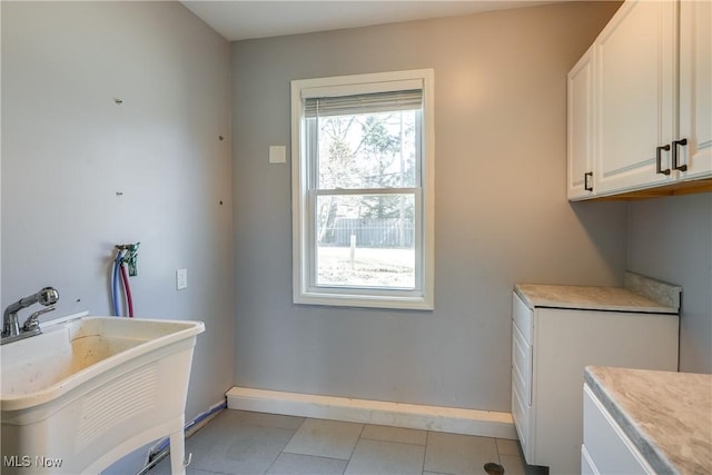 washroom featuring light tile patterned floors, cabinet space, baseboards, and a sink