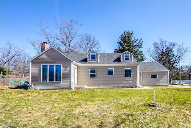 rear view of house featuring a lawn, a shingled roof, a chimney, and fence