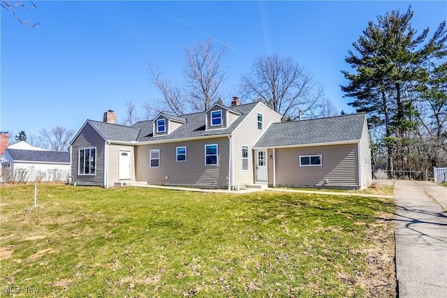 back of property featuring entry steps, a chimney, a yard, and a shingled roof