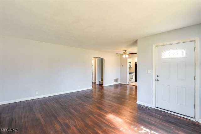 foyer with visible vents, baseboards, dark wood-style floors, arched walkways, and a ceiling fan