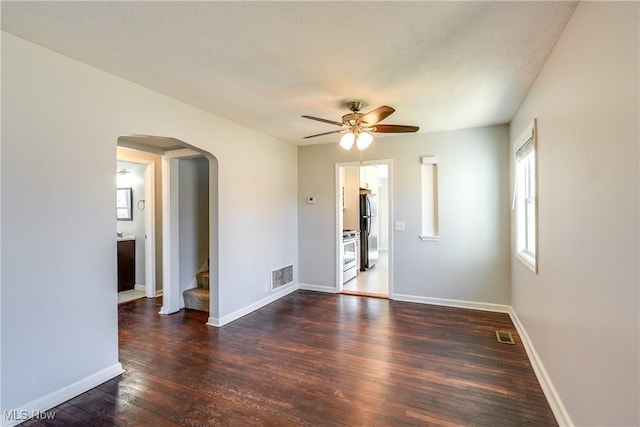 spare room with a ceiling fan, visible vents, baseboards, arched walkways, and hardwood / wood-style flooring