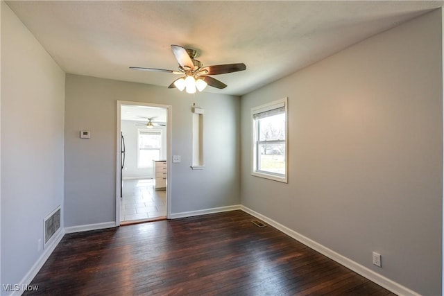 spare room with visible vents, baseboards, dark wood finished floors, and a ceiling fan