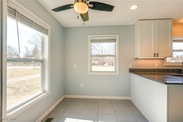 interior space featuring dark stone counters, white cabinets, and a wealth of natural light