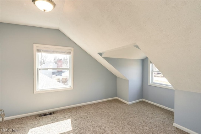 bonus room with lofted ceiling, carpet flooring, baseboards, and visible vents