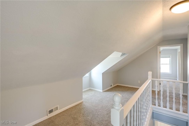 bonus room with visible vents, baseboards, lofted ceiling with skylight, carpet flooring, and a textured ceiling