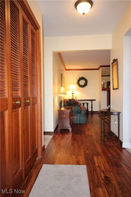 corridor with wood finished floors, baseboards, and ornamental molding