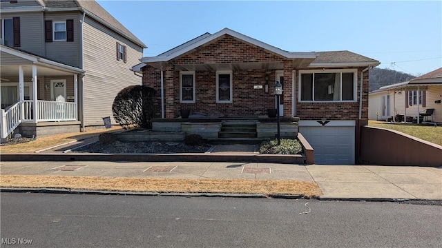 view of front of home featuring a garage, brick siding, a porch, and concrete driveway