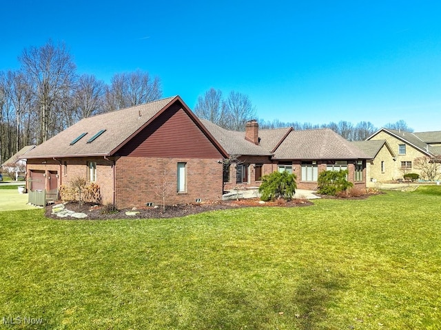 back of house with brick siding, a lawn, and a chimney