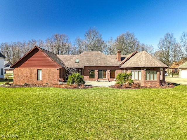 rear view of house with a yard, brick siding, a chimney, and a shingled roof