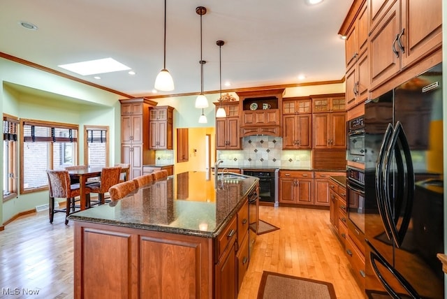 kitchen featuring decorative backsplash, brown cabinets, black appliances, and a sink