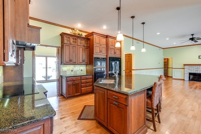 kitchen with black appliances, a brick fireplace, and brown cabinetry