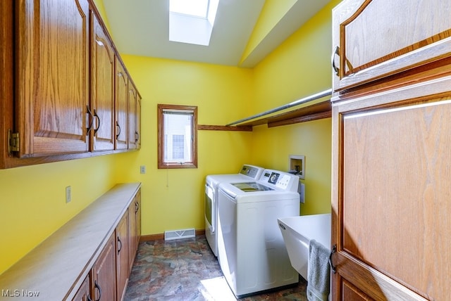 laundry room featuring independent washer and dryer, stone finish flooring, cabinet space, a skylight, and baseboards