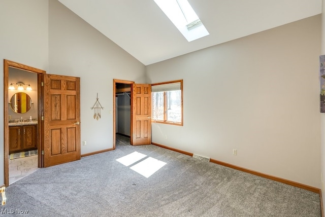 unfurnished bedroom featuring a spacious closet, visible vents, carpet flooring, a skylight, and high vaulted ceiling