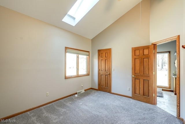 unfurnished bedroom featuring visible vents, high vaulted ceiling, a skylight, carpet flooring, and baseboards