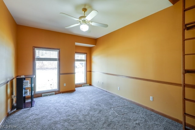 carpeted empty room with visible vents, baseboards, and ceiling fan