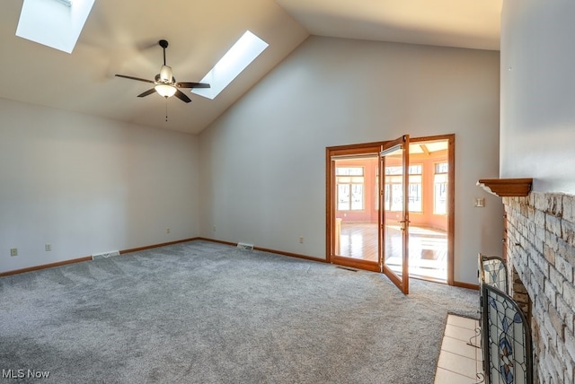 unfurnished living room featuring high vaulted ceiling, a ceiling fan, carpet, a skylight, and baseboards