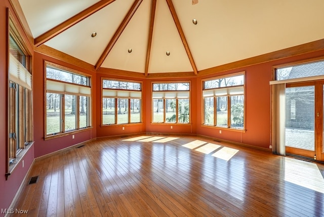 unfurnished sunroom with vaulted ceiling with beams, visible vents, and a wealth of natural light