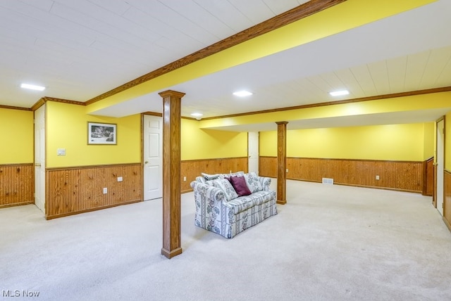 finished below grade area with a wainscoted wall, visible vents, carpet, wood walls, and crown molding