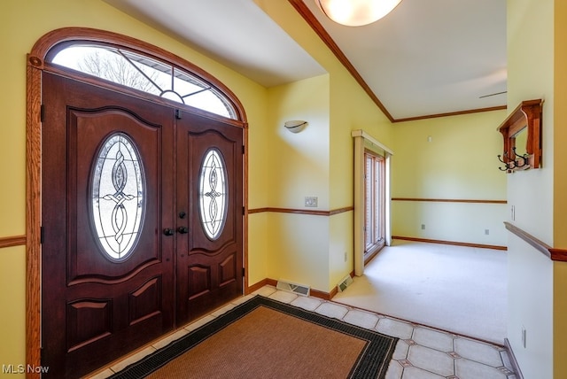 entrance foyer with crown molding, visible vents, and baseboards