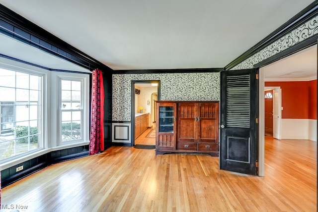 unfurnished living room featuring light wood finished floors, wallpapered walls, and crown molding