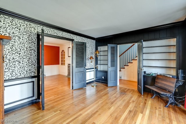 interior space with light wood-style flooring, stairs, and ornamental molding