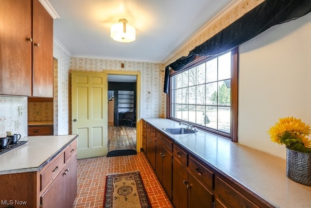 kitchen with wallpapered walls, crown molding, brick floor, and a sink