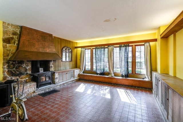 unfurnished living room featuring wood walls and a wood stove