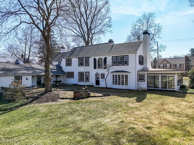 back of property featuring a patio, a yard, a sunroom, and a chimney