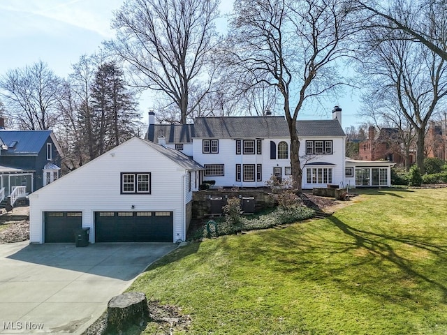 view of front facade with a garage, a front lawn, concrete driveway, and a chimney