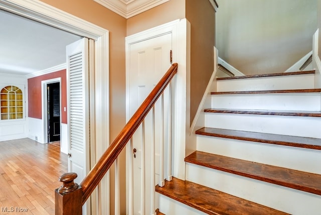 stairs featuring a wainscoted wall, wood finished floors, and crown molding