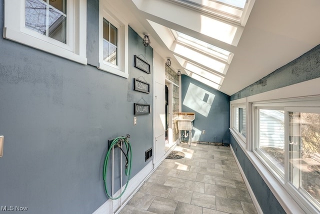 interior space with visible vents, vaulted ceiling with skylight, and baseboards