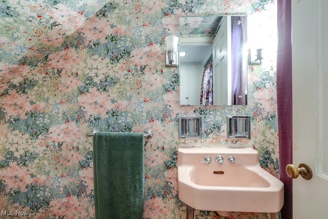 bathroom with wallpapered walls and a sink