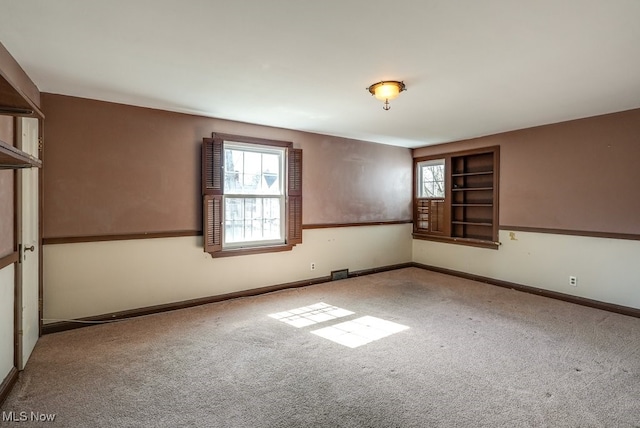 unfurnished room with visible vents, baseboards, and carpet floors