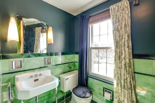 bathroom featuring plenty of natural light, toilet, tile walls, and a sink