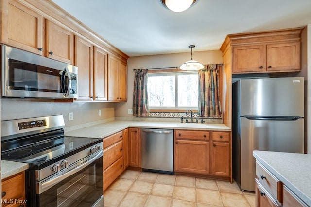 kitchen featuring brown cabinets, pendant lighting, a sink, stainless steel appliances, and light countertops