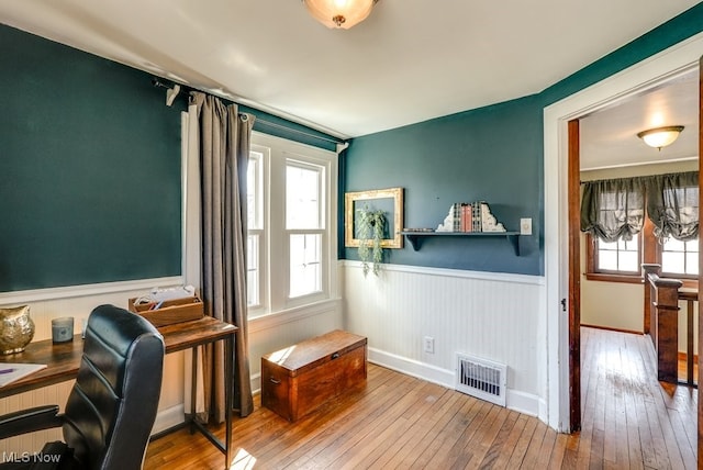 home office with visible vents, a wainscoted wall, and hardwood / wood-style flooring