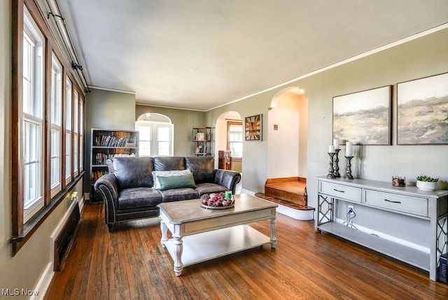 living room featuring baseboards, arched walkways, dark wood-style floors, and ornamental molding