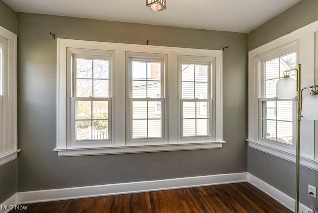 spare room with dark wood finished floors and baseboards