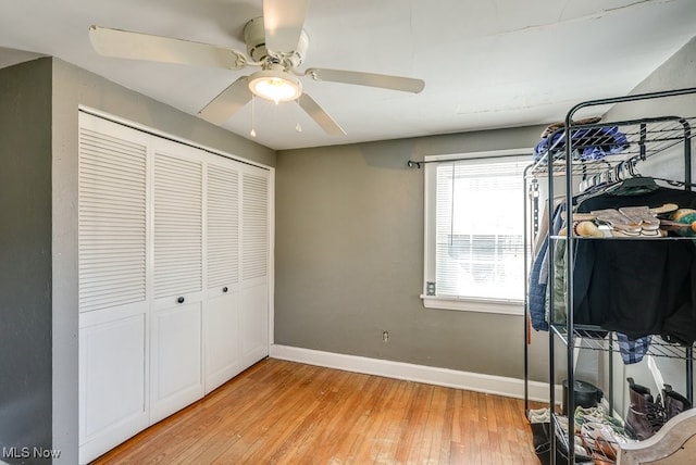 bedroom with a closet, ceiling fan, light wood-type flooring, and baseboards