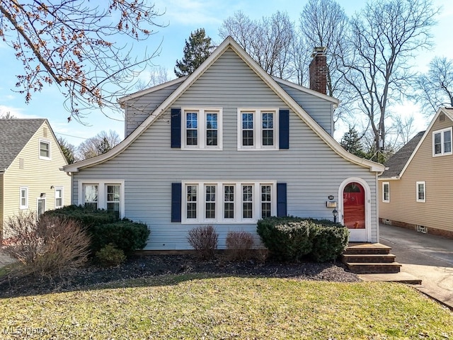 view of front of property featuring a front lawn, driveway, and a chimney