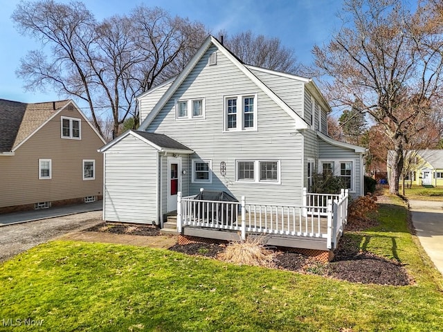 back of property with a wooden deck and a lawn