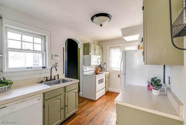 kitchen featuring white appliances, light countertops, green cabinets, and a sink