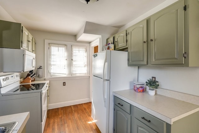 kitchen with white appliances, baseboards, green cabinetry, light wood-style flooring, and light countertops