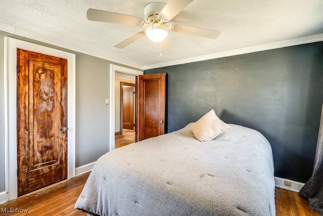 bedroom with wood finished floors, baseboards, ceiling fan, a textured ceiling, and crown molding