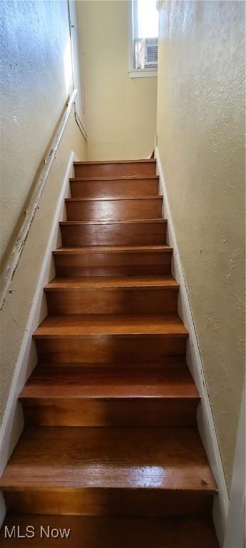 stairs featuring cooling unit and a textured wall