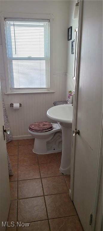 bathroom with toilet, a healthy amount of sunlight, wainscoting, and tile patterned flooring