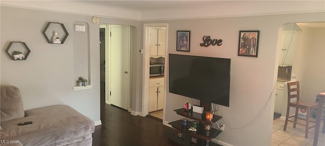 living room with baseboards, arched walkways, and wood finished floors