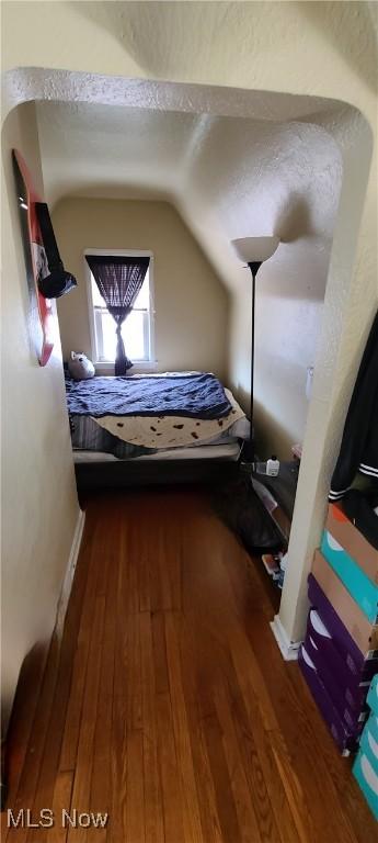 unfurnished bedroom with vaulted ceiling, wood-type flooring, and a textured ceiling