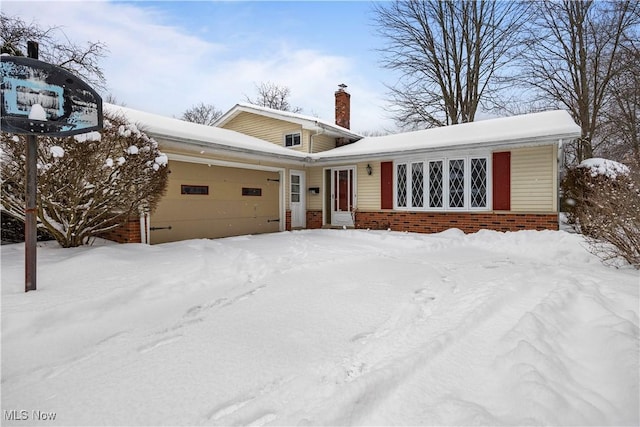 view of front of property with brick siding, a chimney, and a garage